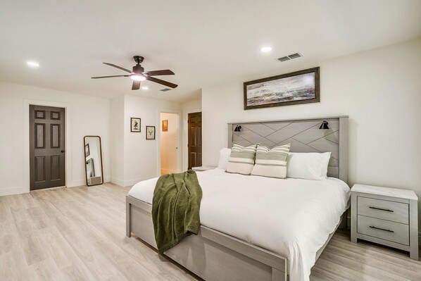A bedroom with a bed, bedside tables, a ceiling fan, and a framed picture on the wall. - 4BR · Sleeps 9 · Walk to Tarleton · Fenced Yard (Stephenville)