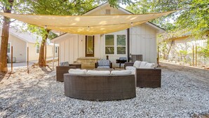 A covered outdoor seating area with wicker furniture and a house in the background.