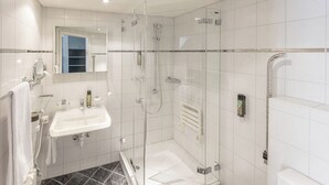 Un baño moderno con ducha acristalada, lavabo blanco y bañera.