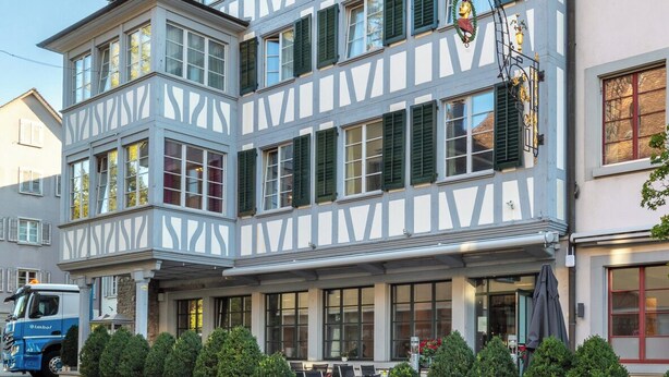 Un edificio tradicional con entramado de madera, múltiples ventanas y un balcón.