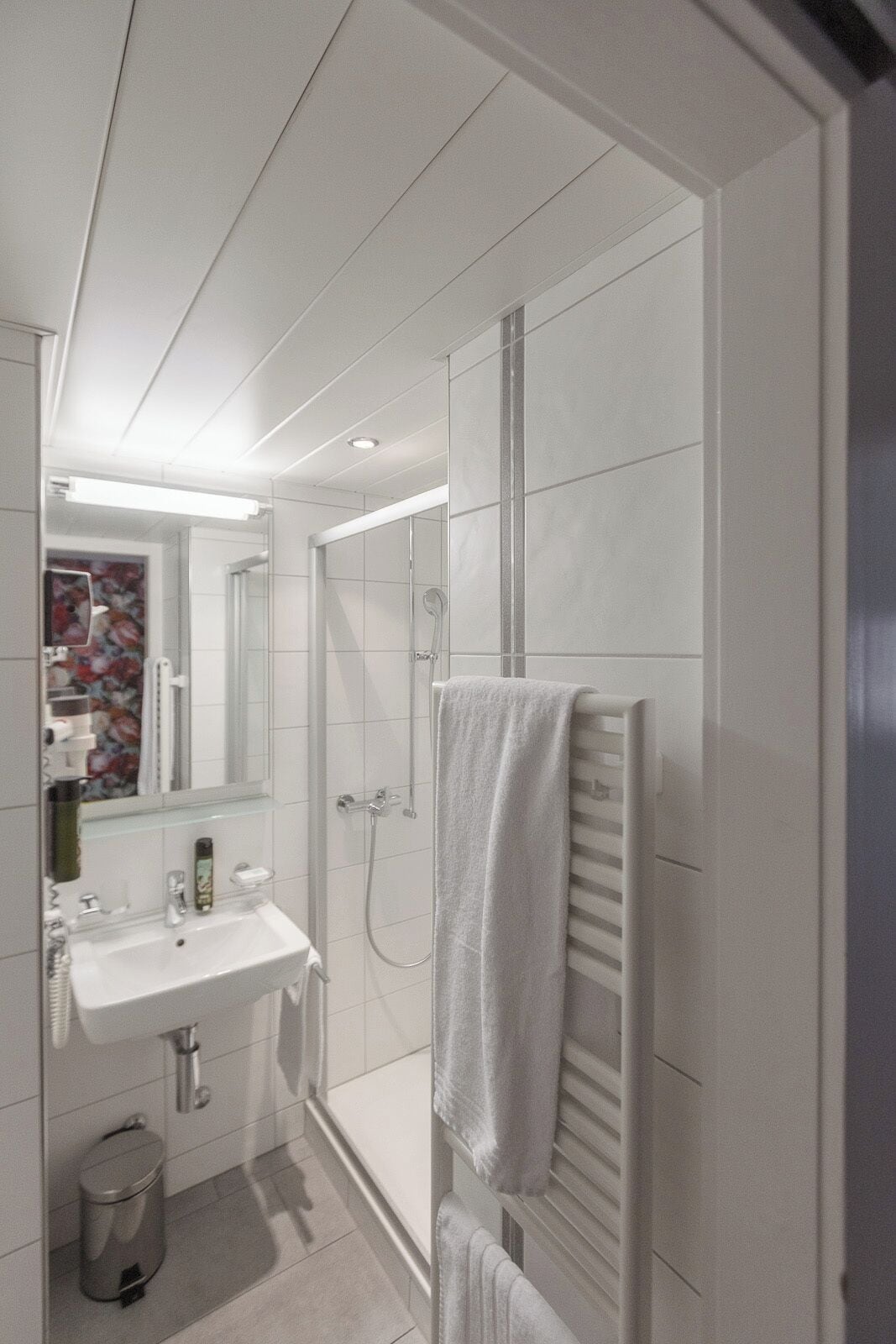 Ein modernes Badezimmer mit Waschbecken, Spiegel und Handtuchhalter.