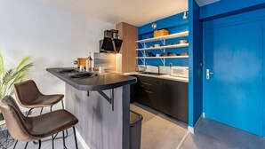 Et moderne køkken med en central ø, sorte skabe og blå detaljer.