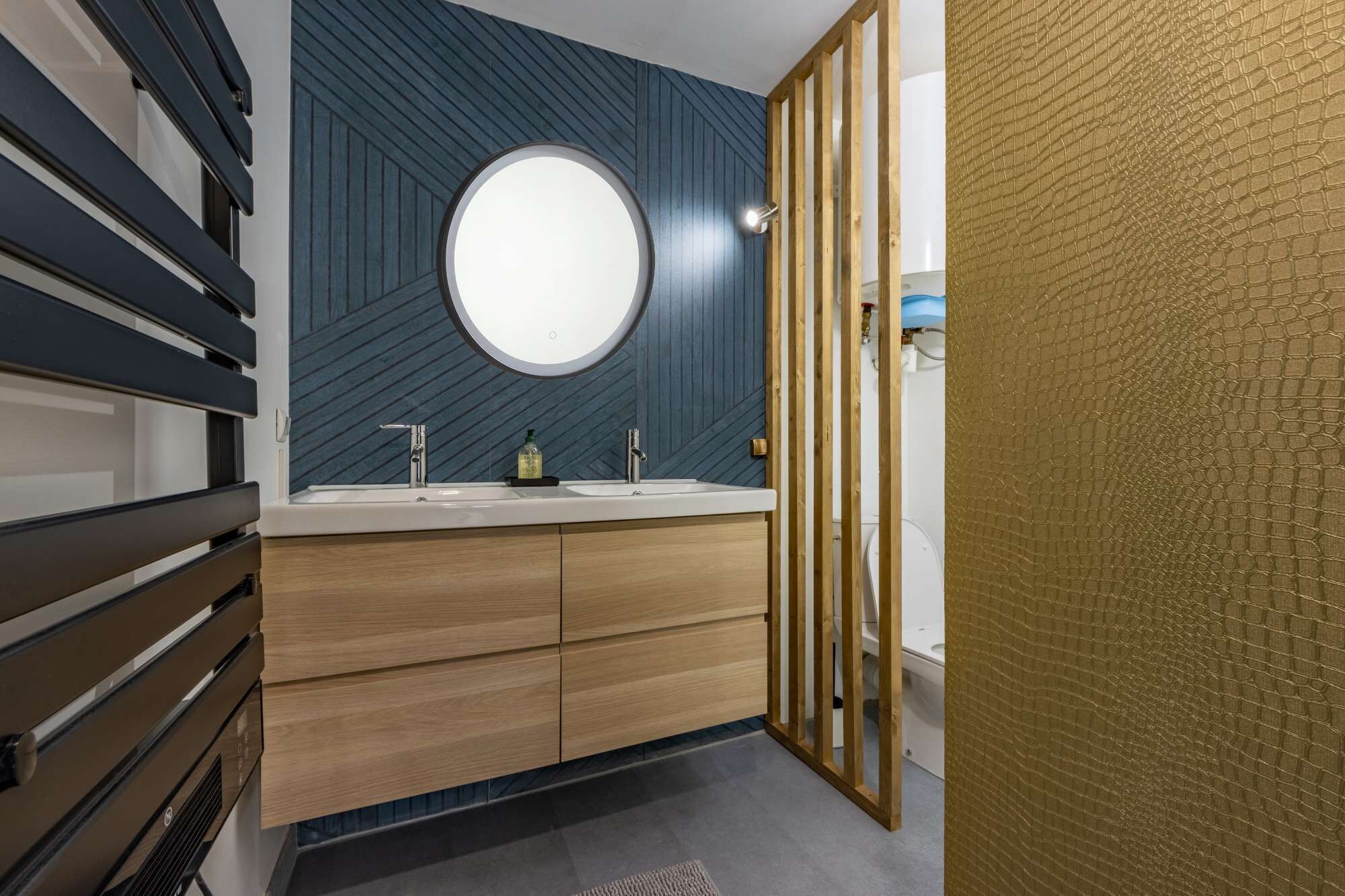Une salle de bain moderne avec un meuble-lavabo en bois, un miroir rond et un lavabo.