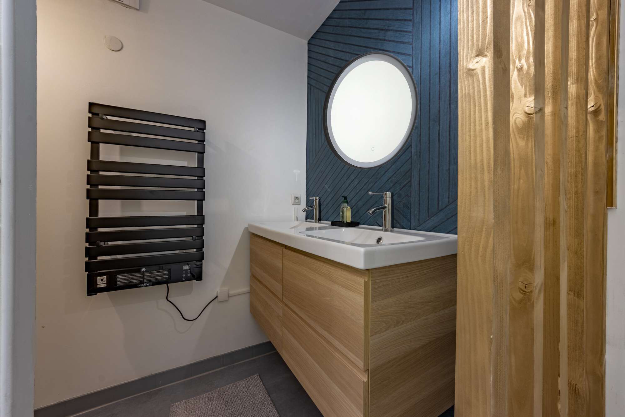 Un baño con calefacción integrada, un lavabo con espejo y armarios de madera.