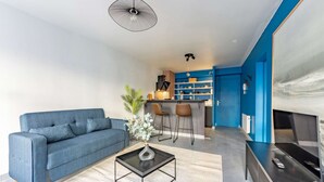 En moderne stue med en blå sofa, et sofabord og et fjernsyn.