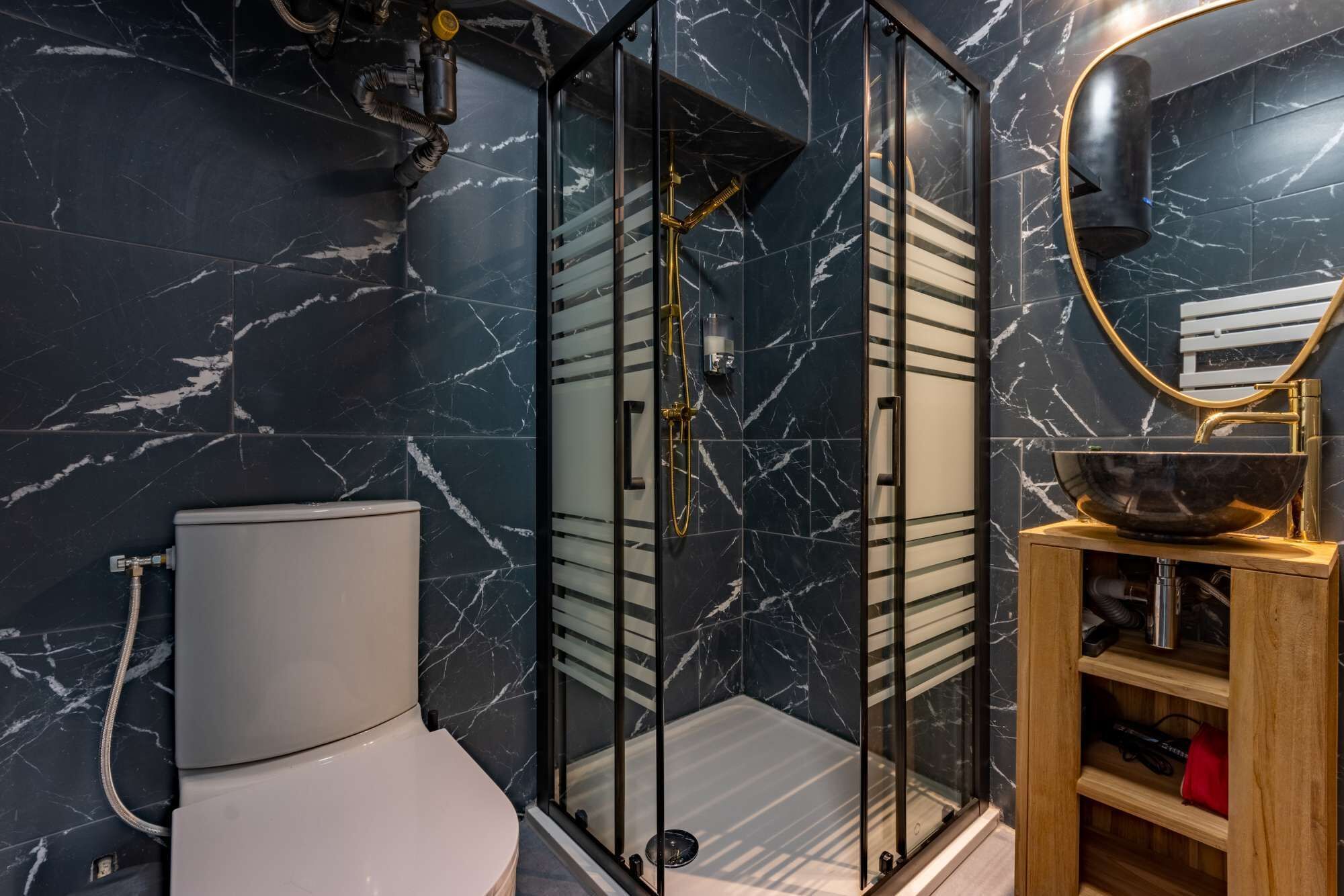 A modern bathroom with a glass-enclosed shower, a white toilet, and a wooden vanity with a bowl sink.