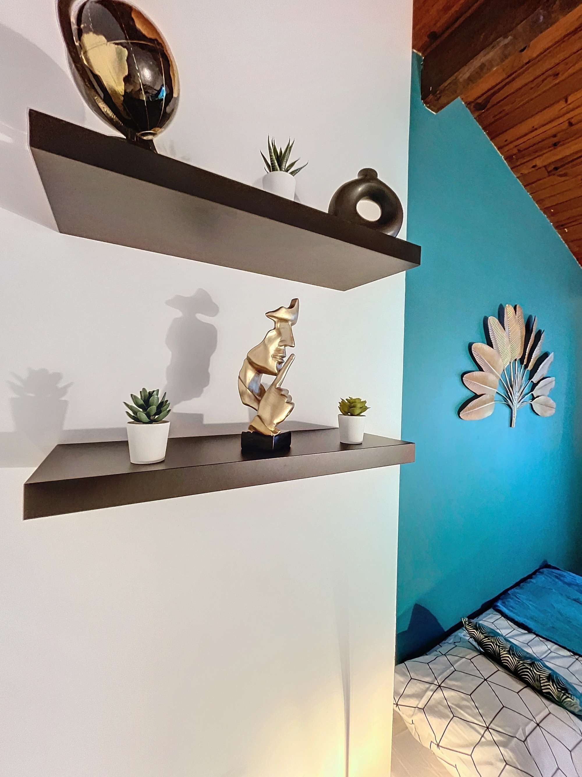 Un interior moderno con dos estantes flotantes color café oscuro, cada uno con objetos decorativos y pequeñas macetas.