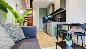 A modern living room with a sofa, a dining table, and a staircase leading to a kitchen. - [Solstice] Street Art - Duplex - Hypercentre (Pamiers)