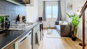 A modern kitchen with a central island, a dining area with a sofa, and a staircase leading to another level. - [Solstice] Street Art - Duplex - Hypercentre (Pamiers)