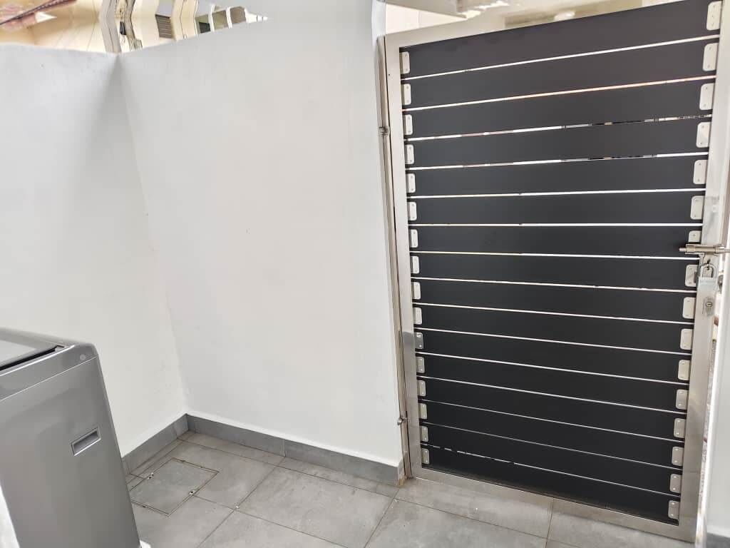 Una habitación con una verja negra cerrada, una pared blanca y un radiador gris.
