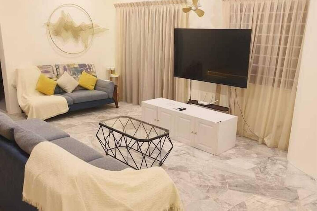 Een woonkamer met een bank, televisie en een decoratief kunstwerk aan de muur.