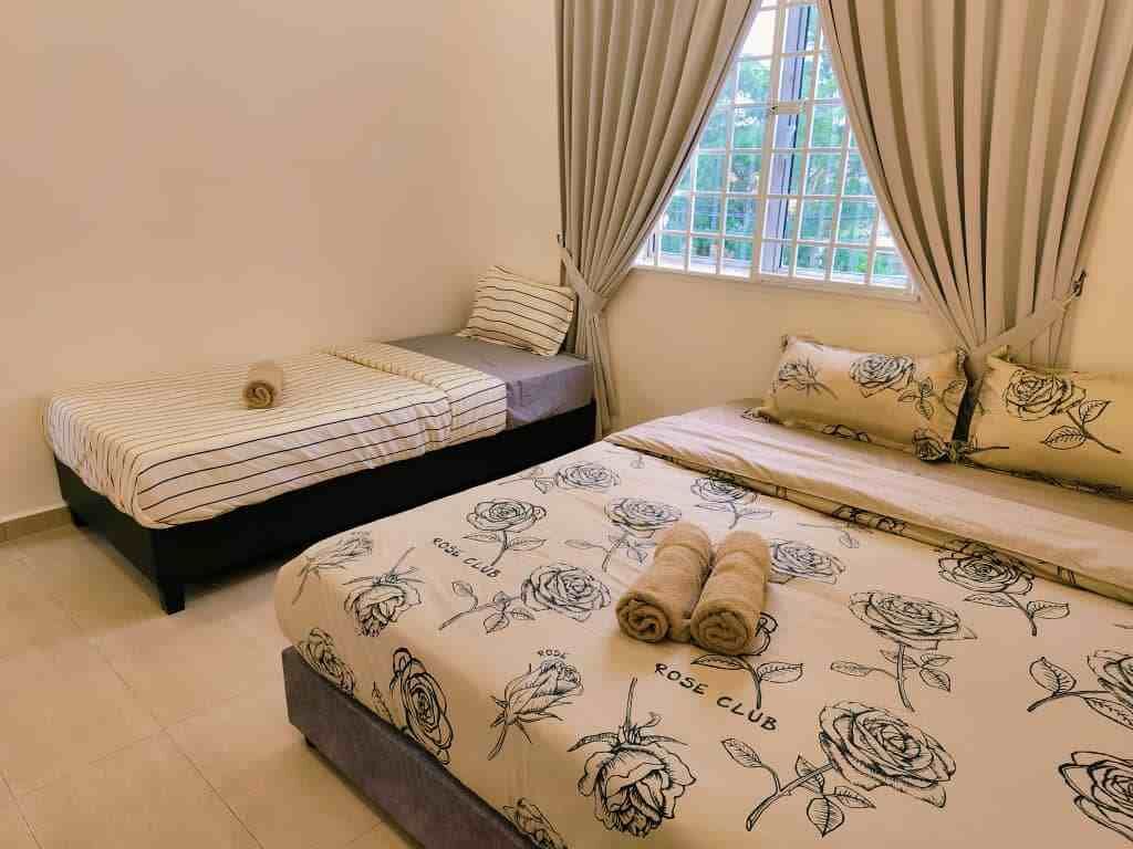 A bedroom with two beds, one with striped bedding and the other with floral patterns.