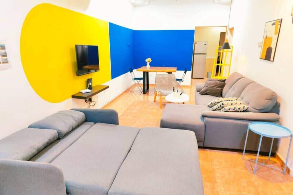 Een kamer met een massagetafel, een bank, een klein tafeltje met stoelen en een televisie.