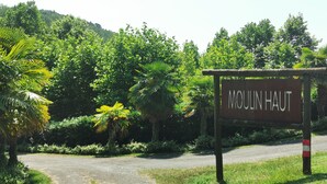 Un cartel con la inscripción 'Moulin Haut' a la entrada de un camino rodeado de abundante vegetación.