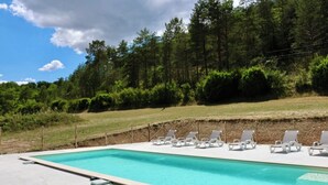 Una piscina rectangular con superficie de agua azul cristalina, rodeada de una solana de hormigón.