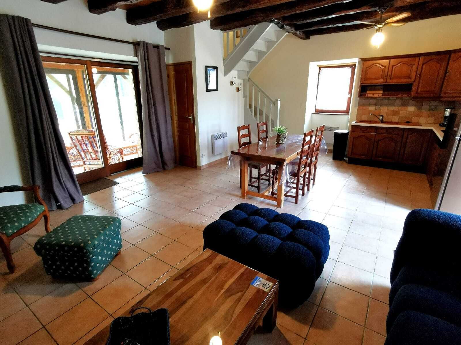 A spacious living area with a wooden dining table and chairs, a staircase leading to an upper floor, and a kitchen with wooden cabinets.