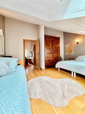 Une chambre avec deux lits, une armoire en bois, une carte accrochée au mur et un grand tapis.