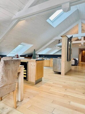 A spacious loft with high ceilings, skylights, a kitchen area, and a cozy seating area.