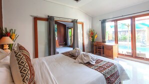 A hotel room with a large bed, a desk, and a view of a swimming pool. - Tranquil Maha Villa Ubud (Ubud)