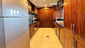 Eine Küche mit Holzschränken, einem Edelstahlkühlschrank und einem gefliesten Boden.