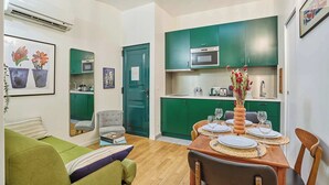 A compact living space with a dining area, kitchenette, and a green sofa. - Charming Duplex Le Marais/beaubourg (Paris)