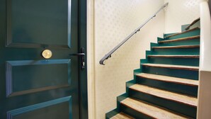 A staircase with wooden steps and a metal handrail, leading to a door with a brass doorknob. - Charming Duplex Le Marais/beaubourg (Paris)