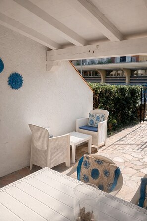 A patio with wicker furniture, a white table, and a glass with a plant. - La Casetta di Gioia 200 m from the sea, garden, fast Wi-Fi (Porto Ottiolu)