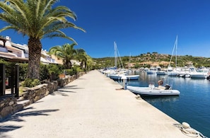 A marina with boats docked, a paved walkway, and a stone wall. - La Casetta di Gioia 200 m from the sea, garden, fast Wi-Fi (Porto Ottiolu)