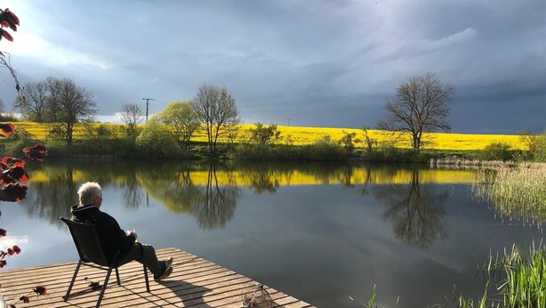 A wooden dock extending into a calm lake with a person seated at the end. - Rostock-Laage Super nice apartment right on the lake! (Laage)