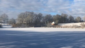 A snow-covered landscape with a small building, trees, and a clear sky. - Rostock-Laage Super nice apartment right on the lake! (Laage)