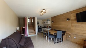 Un espace de vie compact comprenant un coin cuisine, un coin repas et un canapé.