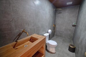 Ein Badezimmer mit einem Holzkosmetikschrank, einer weißen Toilette und einem Duschbereich.