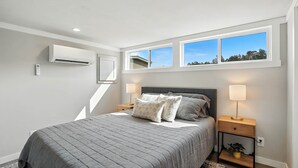 Ein Schlafzimmer mit einem Bett, Nachttischlampen, einer Klimaanlage und einem Fenster mit Blick.
