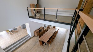 A modern loft-style apartment with a spacious dining area, a lofted seating area, and a visible staircase. - Charming cottage in Southern Vosges, perfect for 14 guests (Les Fessey)