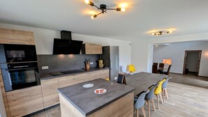 A modern kitchen with a central island, wooden cabinets, and a built-in oven. - Charming cottage in Southern Vosges, perfect for 14 guests (Les Fessey)