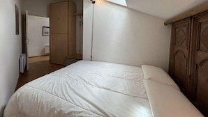 A bedroom with a large bed, a wooden wardrobe, and a skylight. - Cozy apartment for 6 in Montgenèvre, pet-friendly with parking (Montgenèvre)