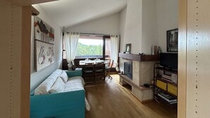 A cozy living room with a sofa, a fireplace, a dining area, and a view of the outdoors. - Cozy apartment for 6 in Montgenèvre, pet-friendly with parking (Montgenèvre)