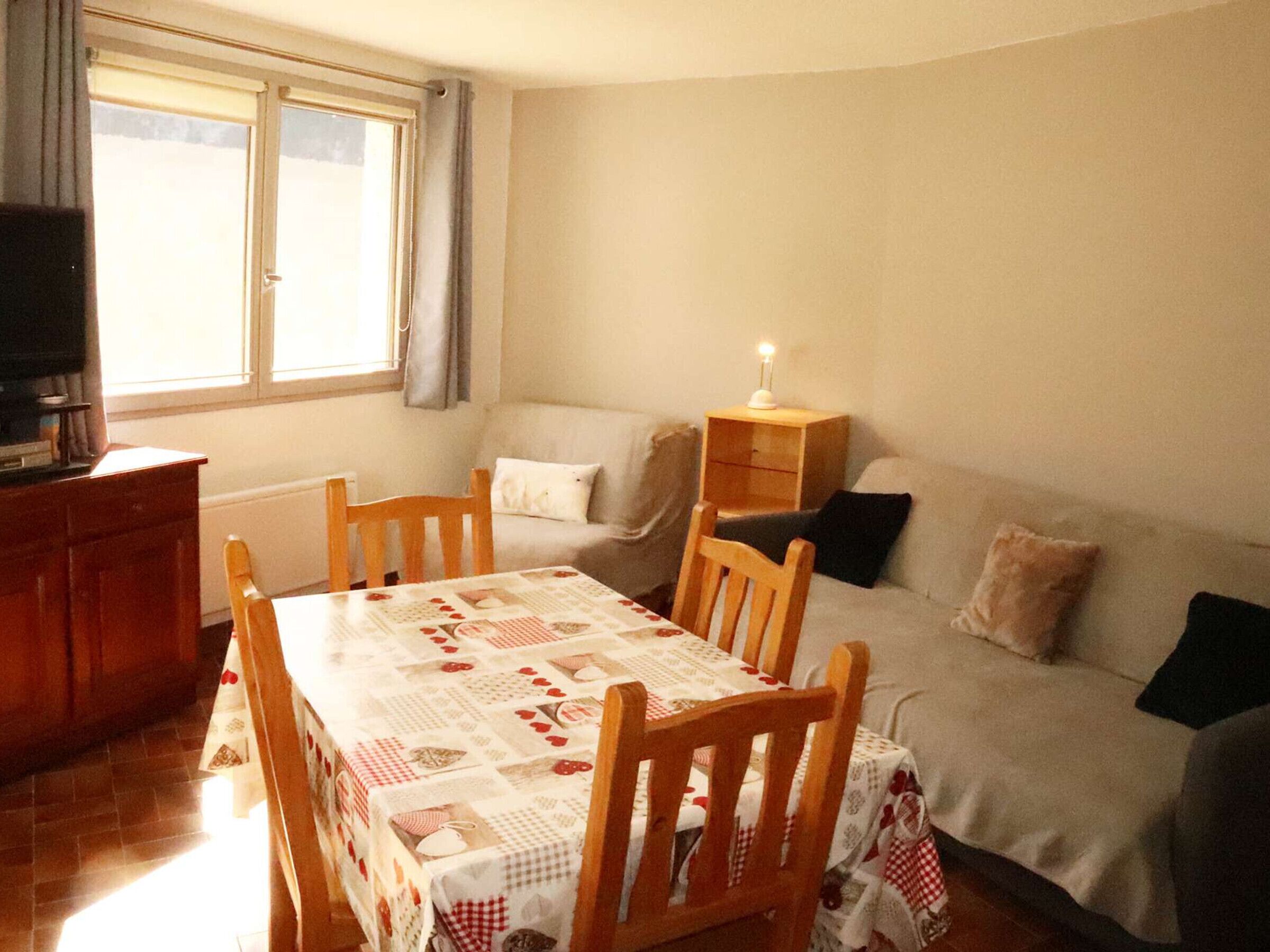 Ein gemütliches Wohnzimmer mit Esstisch, Stühlen, einer Couch und einem Fernseher.