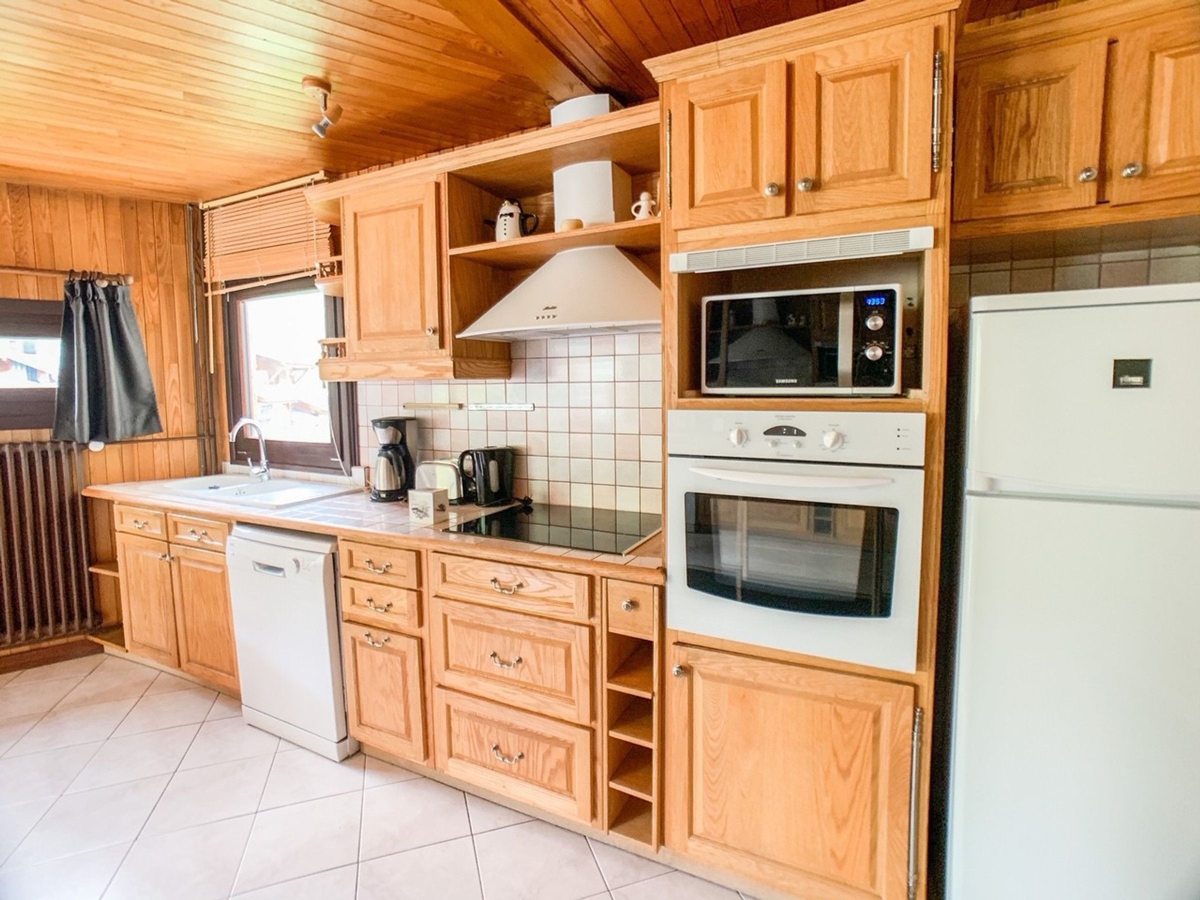 A compact kitchen with wooden cabinets, a microwave, a stove, and a refrigerator.
