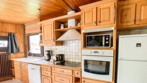 A compact kitchen with wooden cabinets, a microwave, a stove, and a refrigerator.