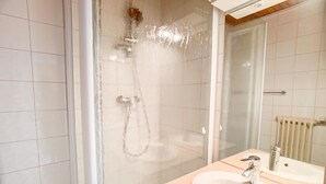 A bathroom with a shower, a sink, and a mirror.
