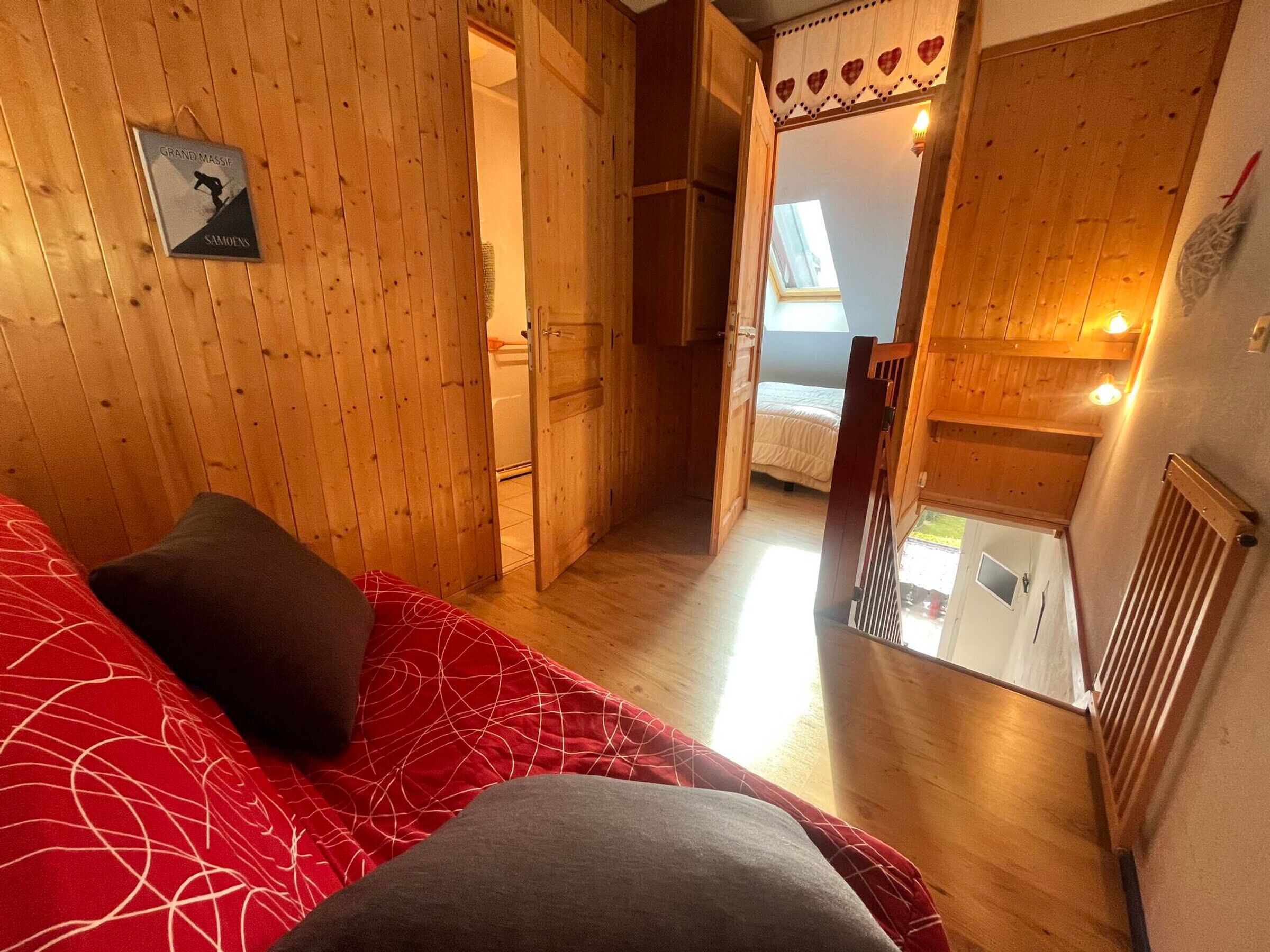 En träinredd interiör med en säng, en dörr som leder ut till en balkong och ett litet bord.
