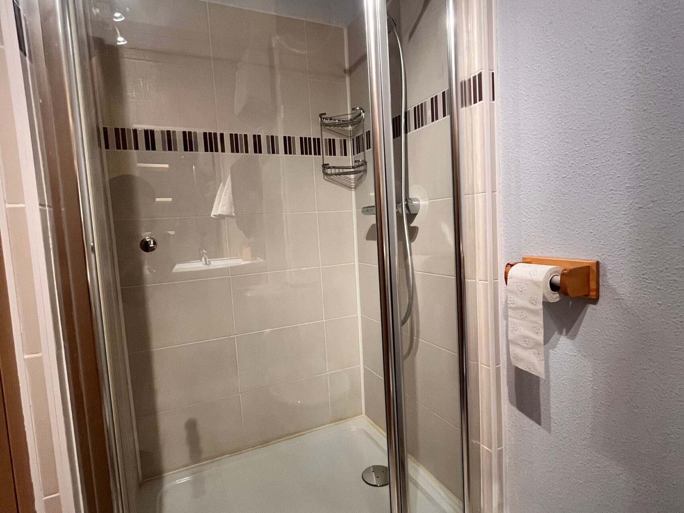 A glass-enclosed shower with a tiled floor and a small sink.