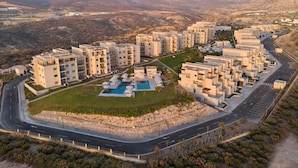 A modern residential complex with multiple apartment buildings, a swimming pool, and a well-maintained road. - Radisson Residences Taghazout Bay (Taghazout)