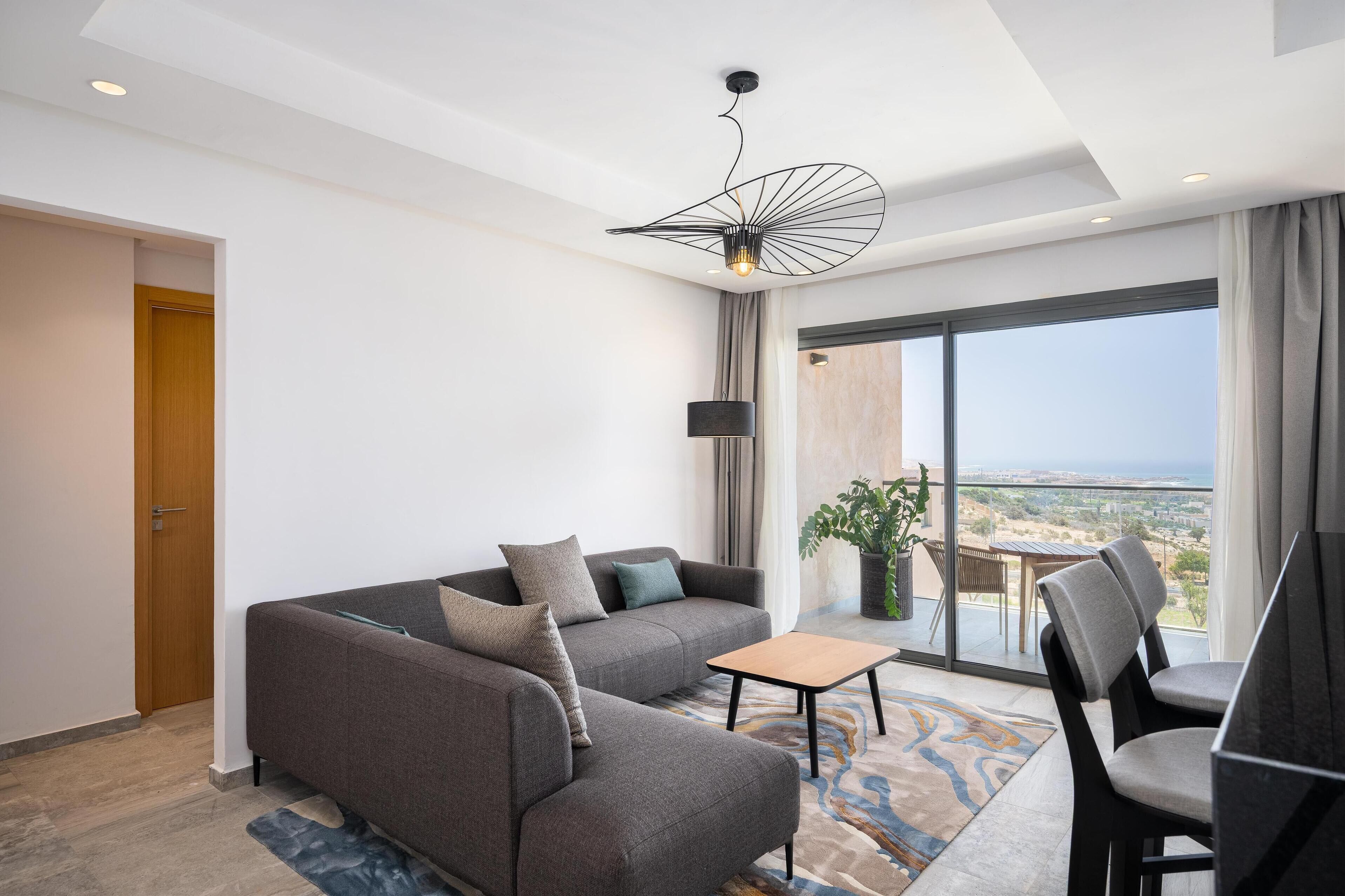 A modern living room with a sofa, a coffee table, and a dining area.