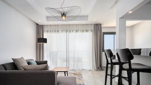 A modern hotel room with a sofa, a small table, and a bar area. - Radisson Residences Taghazout Bay (Taghazout)