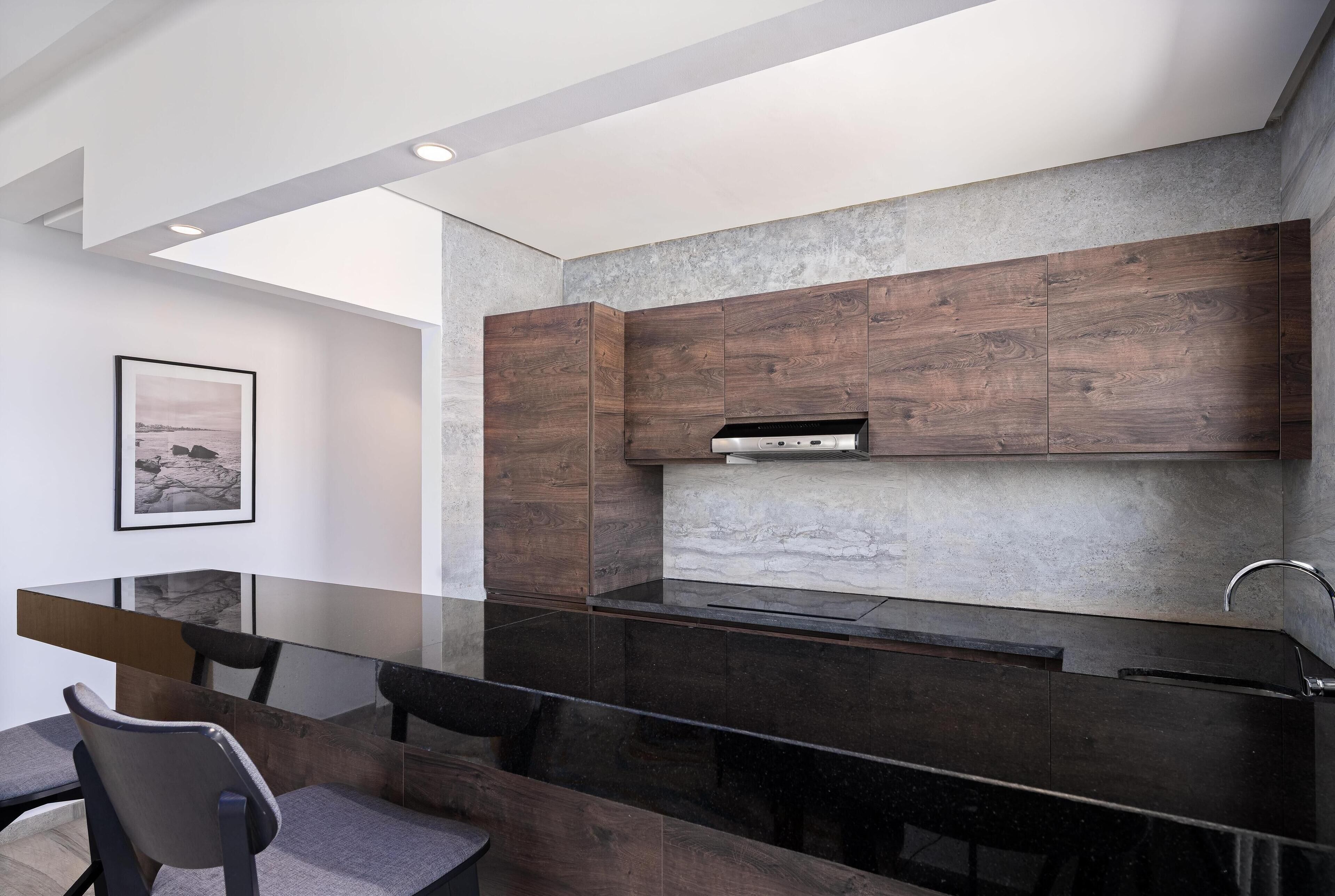 A modern kitchen with dark wood cabinets, a glass dining table, and a stainless steel range hood.