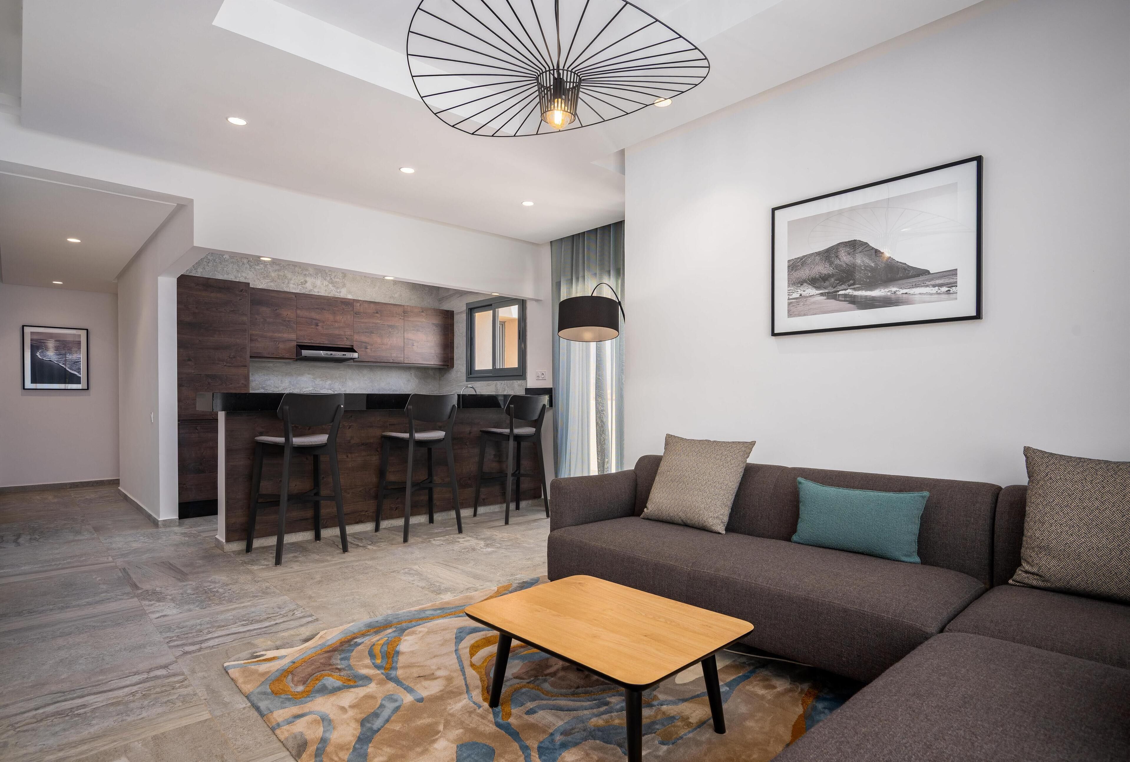 Un salon moderne avec un canapé, une table basse et un coin repas équipé de tabourets de bar.