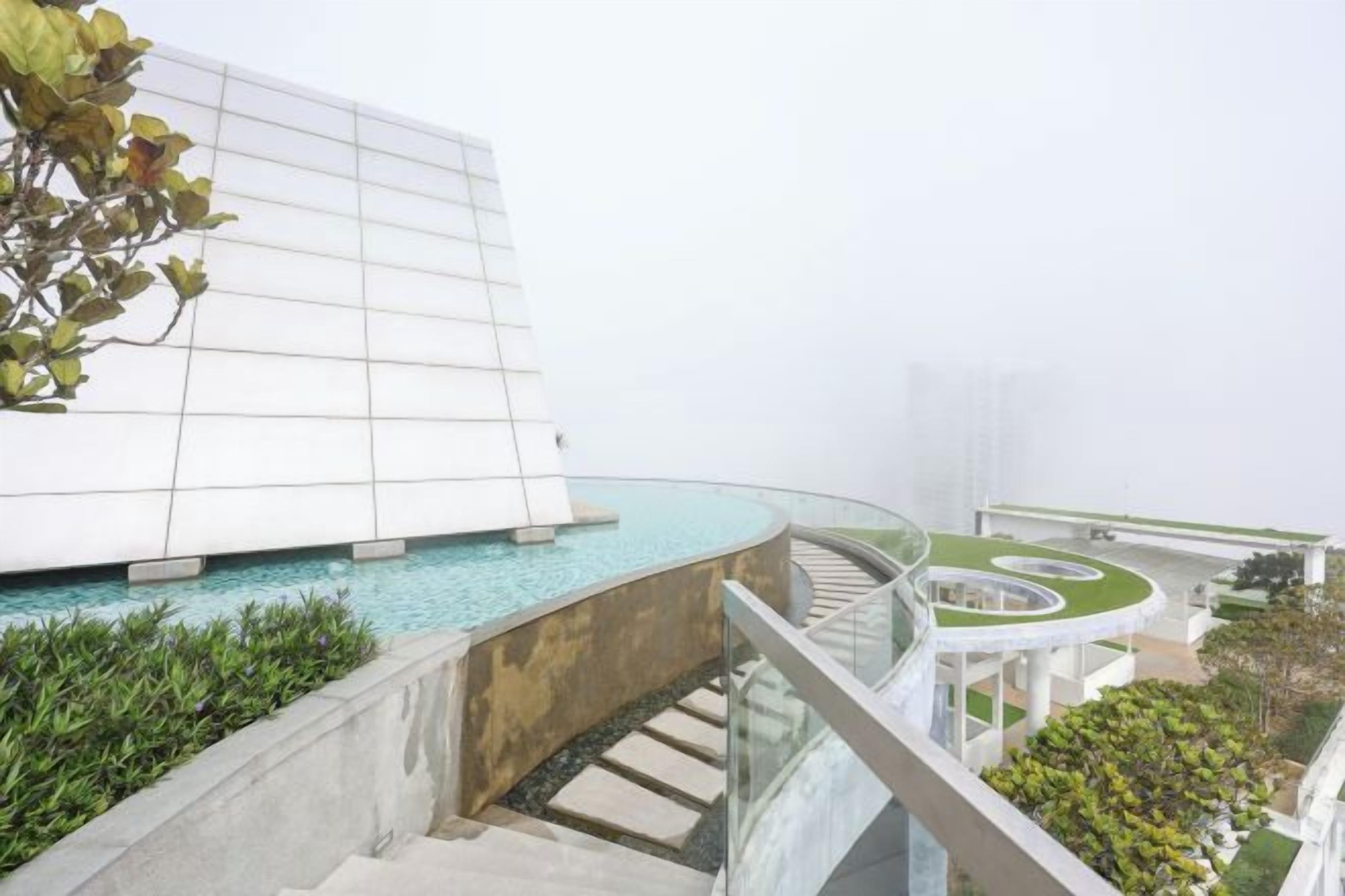 A modern building with a glass facade, a pool, and a spiral staircase.
