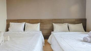 Habitación de hotel con dos camas, cada una con ropa blanca y almohadas, y cabeceros de madera.